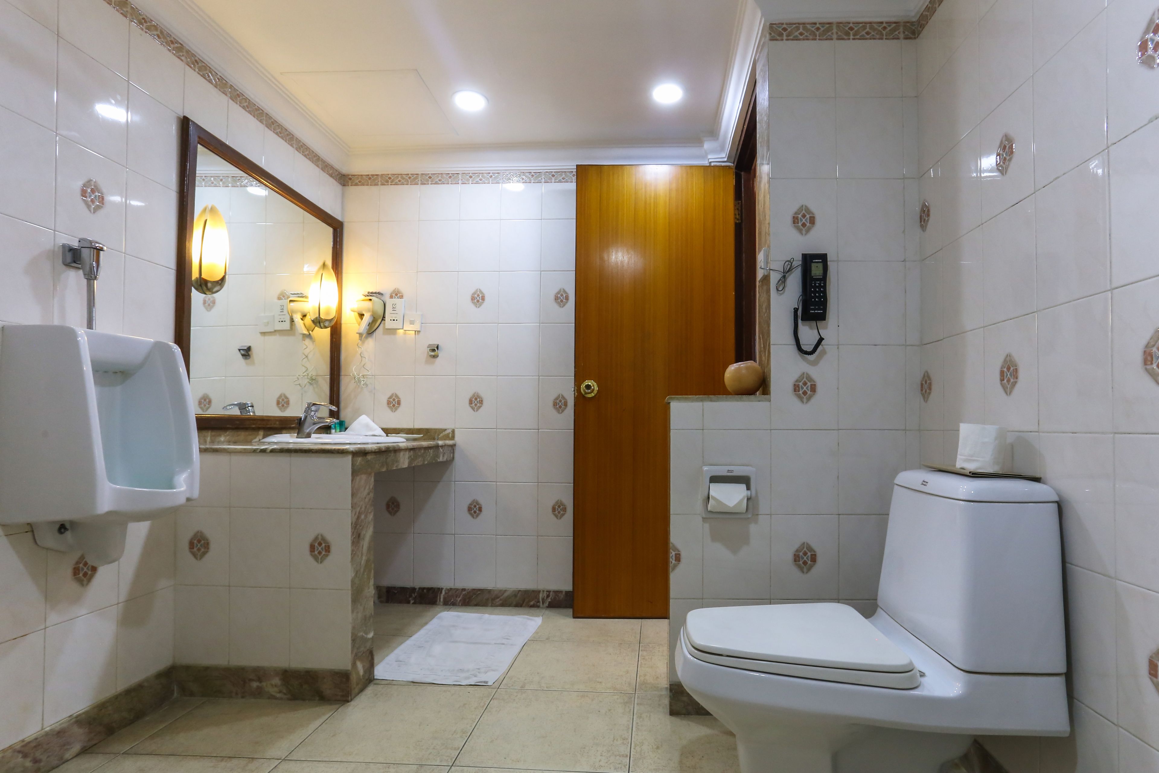 Casa de banho com sanita, lavatório, espelho e secador de mãos.