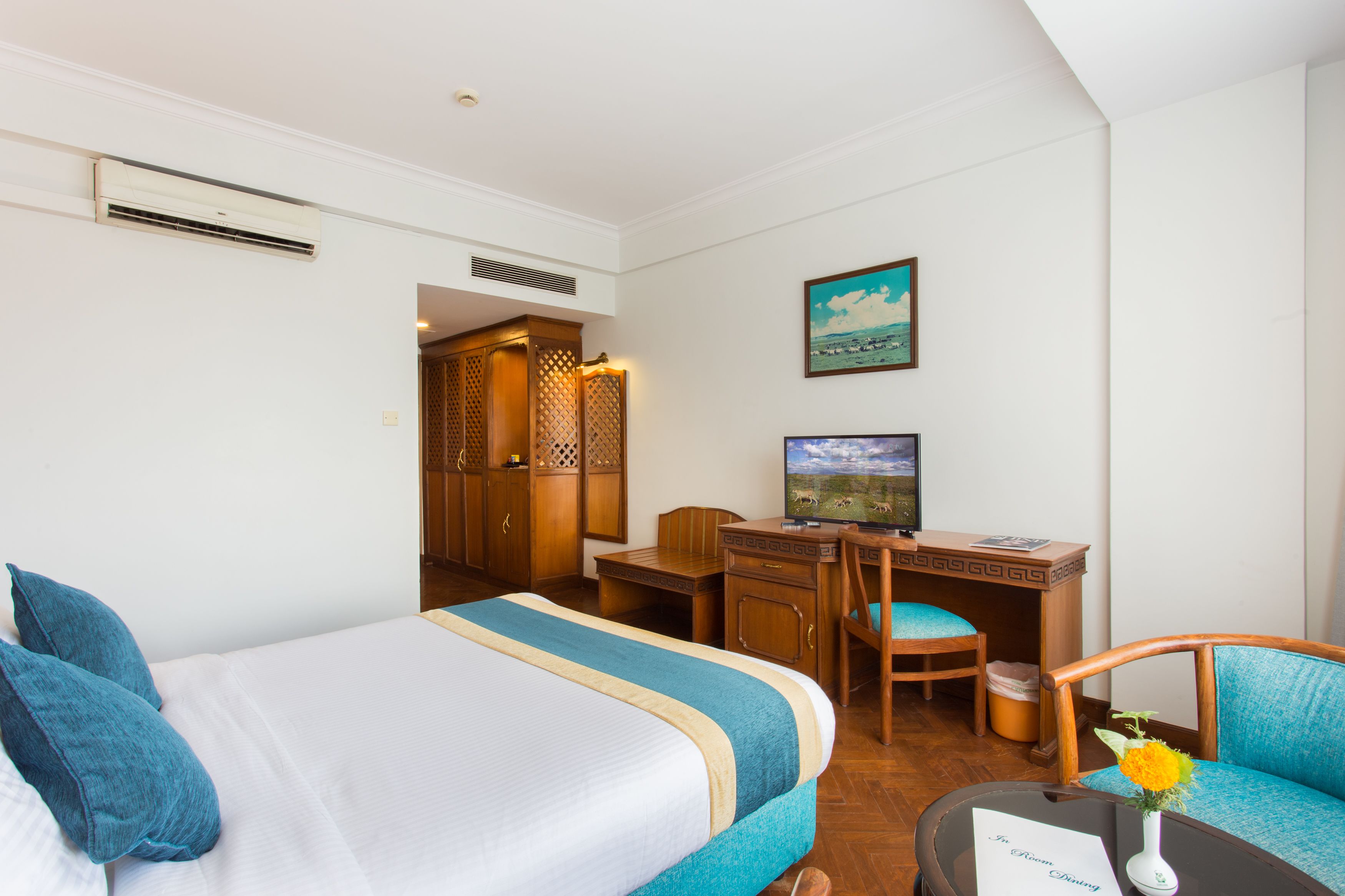 Habitación de hotel con dos camas, un escritorio, una silla, un televisor y un cuadro en la pared.