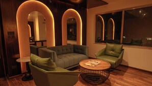 A modern lounge with a sofa, armchairs, a round coffee table, and large arched mirrors. - Hotel Le Himalaya (Kathmandu)