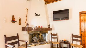 A cozy living room with a fireplace, wooden furniture, and a flat-screen TV mounted on the wall. - Aadonis Villa (Platanias)