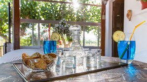 A tray with a glass pitcher, glasses, and a bowl of cookies on a table. - Aadonis Villa (Platanias)