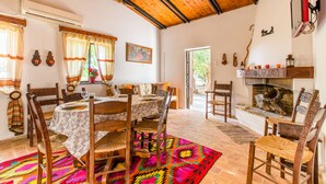 A dining area with a wooden table and chairs, a colorful rug, and a fireplace. - Aadonis Villa (Platanias)