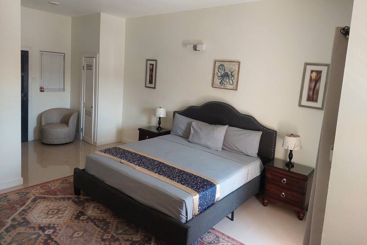 A bedroom with a bed, nightstands, a chair, and a ceiling fan.