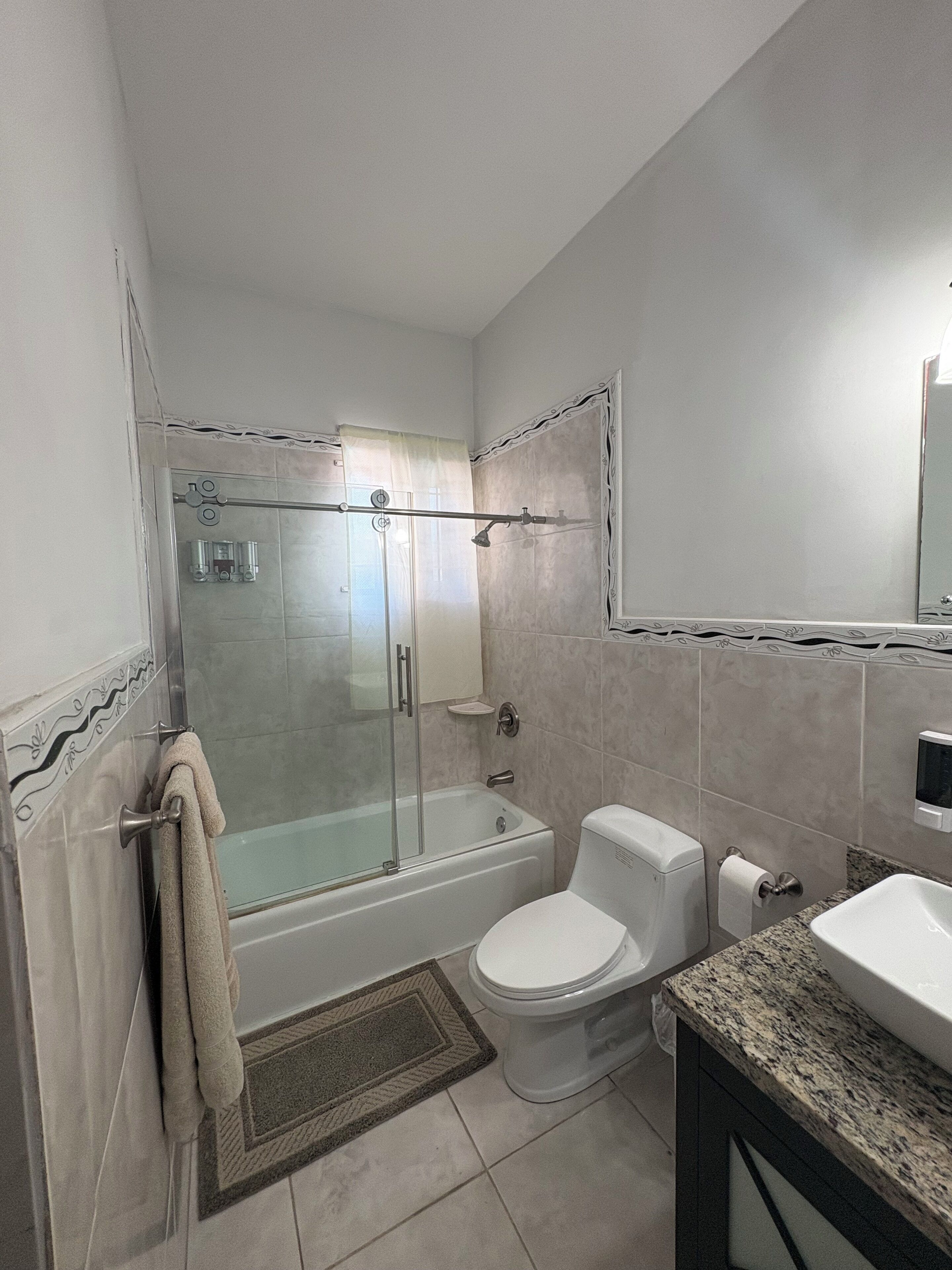 A bathroom with a glass-enclosed shower, a bathtub, a toilet, and a sink.