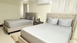 Een hotelkamer met twee bedden, een nachtkastje, een lamp en een airconditioner.
