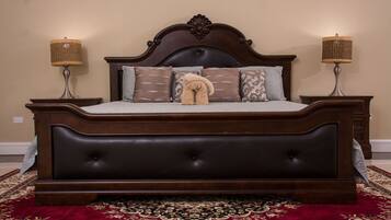 Una cama grande de madera oscura con un cabecero capitonado, dos lámparas de noche y un peluche de oso en las almohadas.