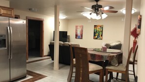 A dining area with a round table, chairs, a refrigerator, and a ceiling fan. - Delta Dome Home Basement Apartment (Delta Junction)
