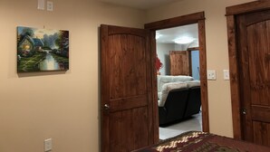 A bedroom with a ceiling fan, a painting of a cottage, and wooden doors. - Delta Dome Home Basement Apartment (Delta Junction)