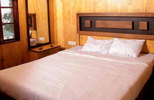 Una habitación con paneles de madera, una cama, una mesita de noche y un espejo.