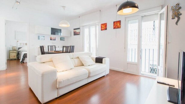 Un salon moderne avec un canapé blanc, un plancher en bois et de grandes fenêtres.