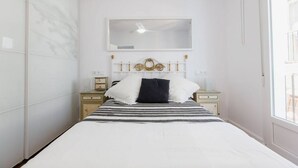Une chambre à coucher avec un lit, une table de chevet, un miroir et une fenêtre.
