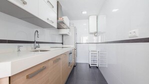 Une cuisine moderne avec des meubles blancs, un évier à deux bacs et un four encastré.