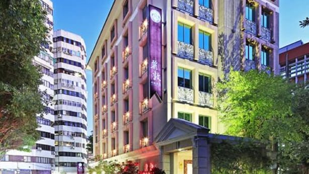 A multi-story hotel with balconies, a parking lot, and a street view. - Reedon Boutique Hotel (Taipei)