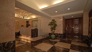 A lobby with a reception desk, a chandelier, a large potted plant, and a checkered floor. - Reedon Boutique Hotel (Taipei)
