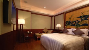 A hotel room with a large bed, a desk with a lamp, a chair, and a television on the wall. - Reedon Boutique Hotel (Taipei)