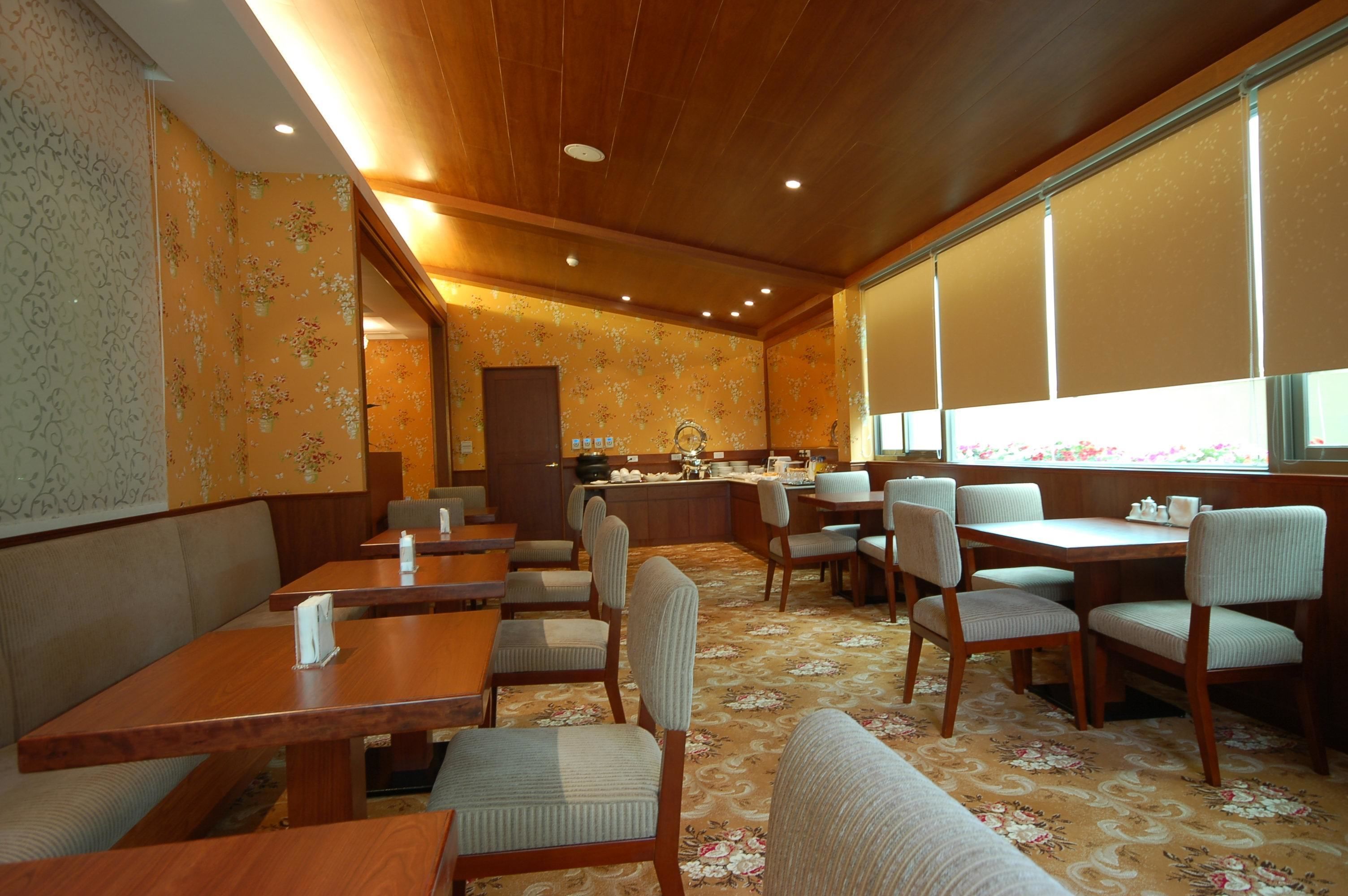 A restaurant with wooden tables and chairs, a counter, and a patterned carpet.