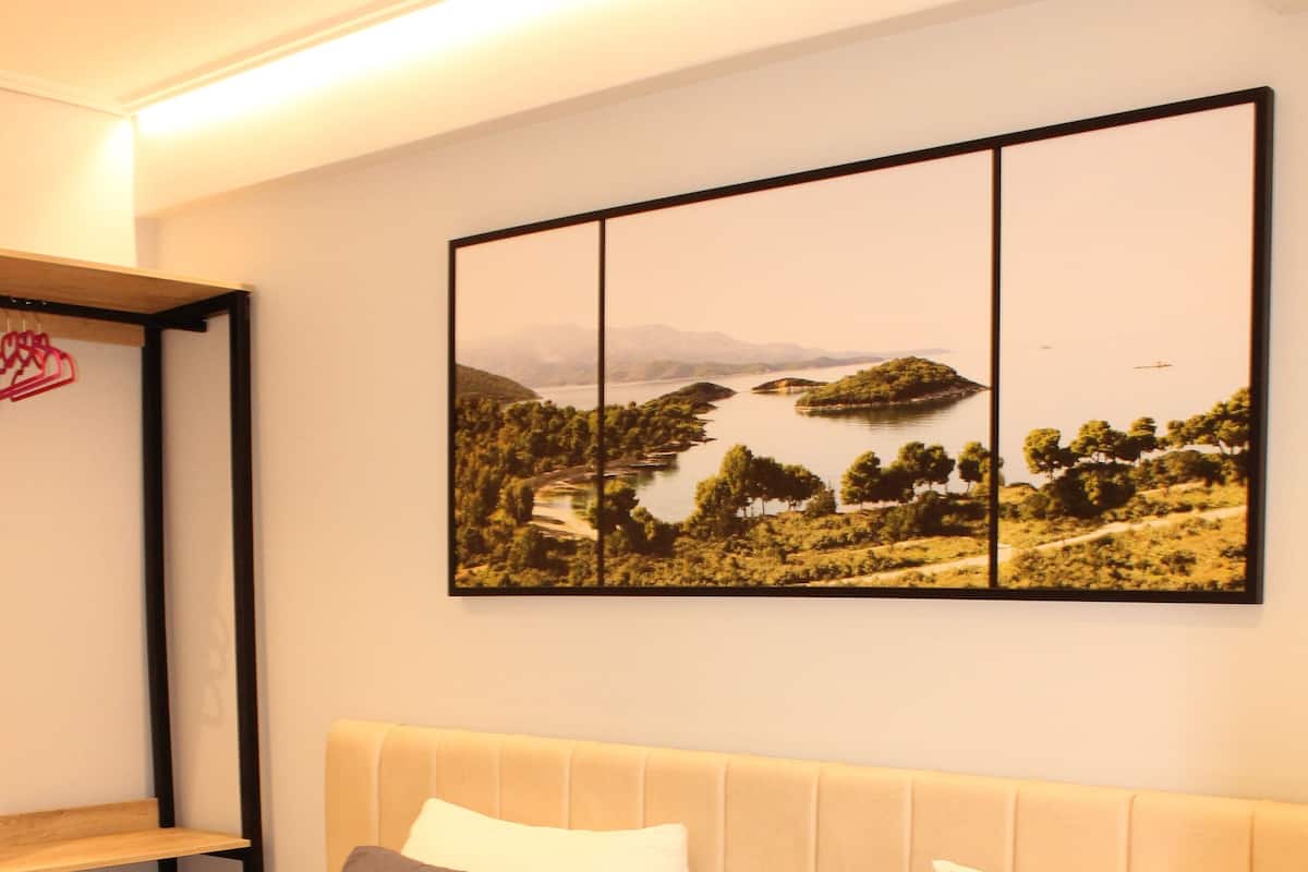 A hotel room with two beds, a large landscape painting, and a towel on the bed.