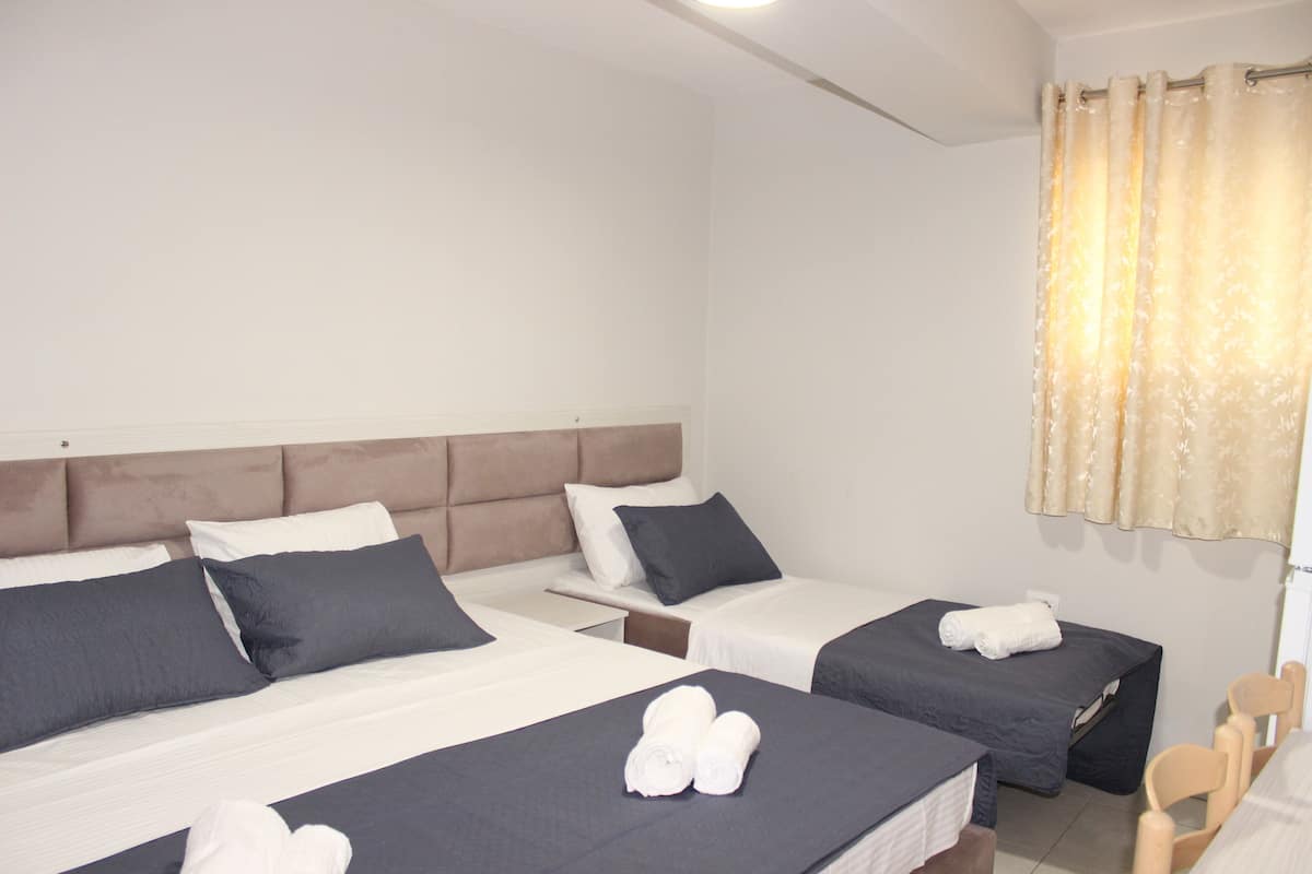 A hotel room with two beds, a headboard, a small table, and a chair.