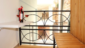 A balcony with a wooden floor, a metal railing, and a bottle of wine on a white table. - Bebi Apartments (Sarandë)