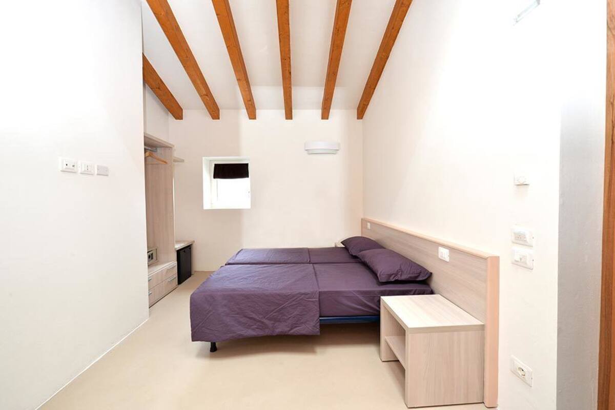 Une petite chambre à coucher moderne, avec un lit, une table de chevet et une armoire.