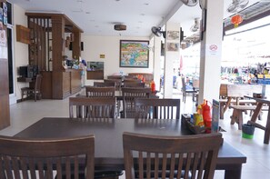 Un restaurante con mesas y sillas de madera, una barra y vistas a un mercado al aire libre.