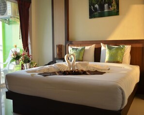 Habitación de hotel con una cama bien hecha, un cuadro de una cascada en la pared y una ventana con cortinas.