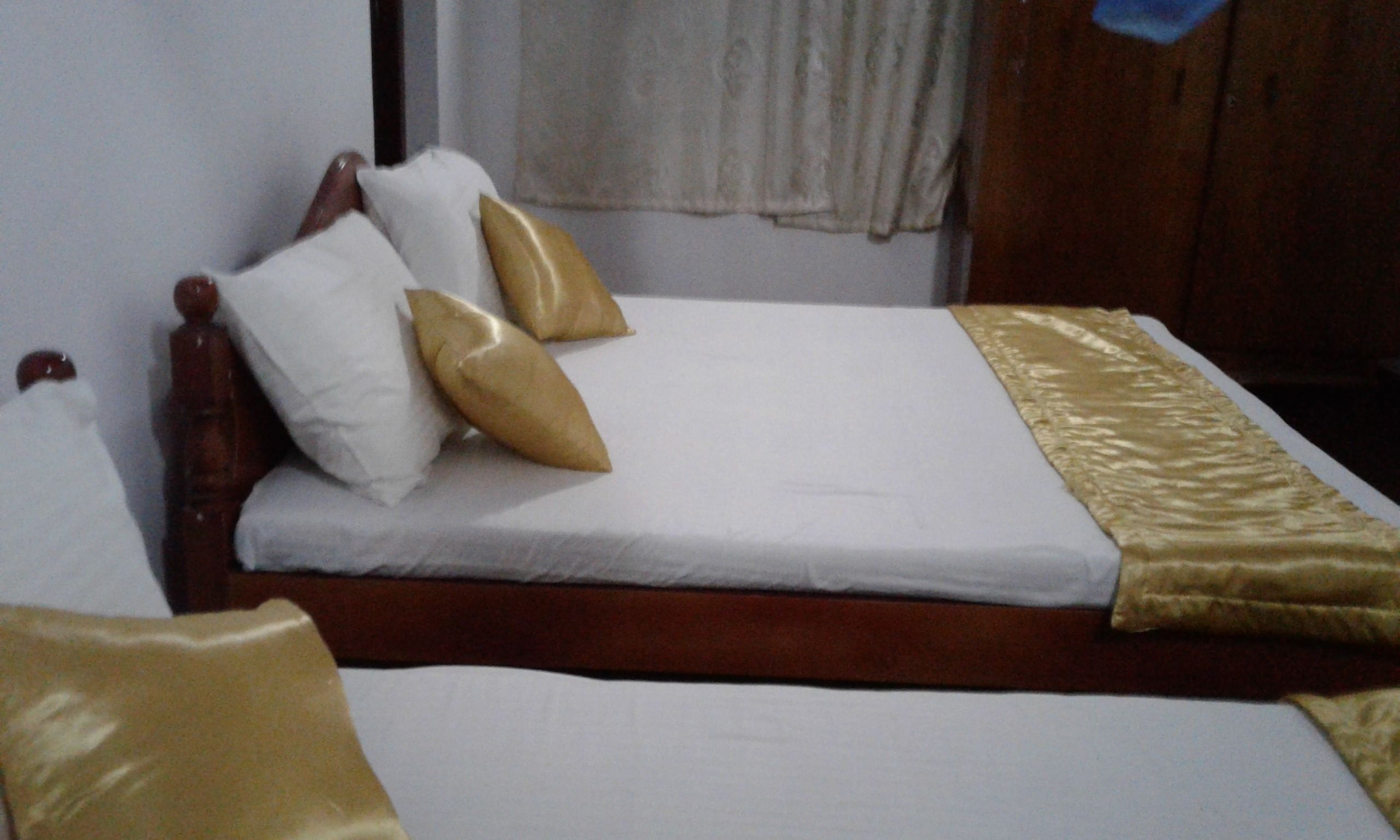 A bed with white bedding and two gold-colored pillows.