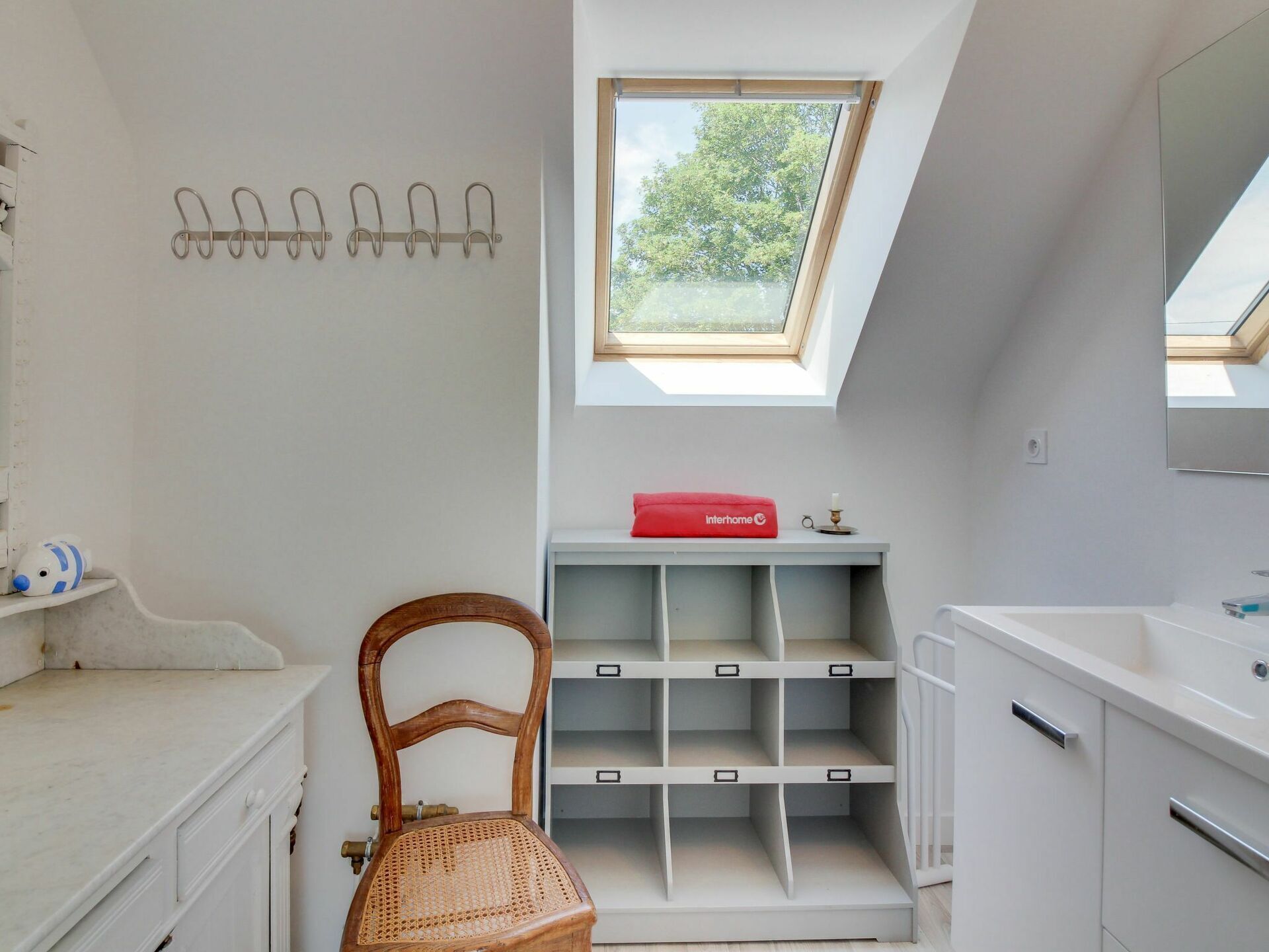 A compact bathroom with a skylight, a chair, and storage units.