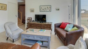 A living room with a television, a sofa, a chair, and a coffee table. - Beautiful private villa for 8 guests with WIFI, TV, terrace and pets allowed (Port Blanc)