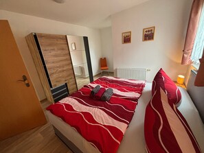 Une chambre à coucher comprenant un lit, une armoire, un radiateur et deux tableaux encadrés accrochés au mur.