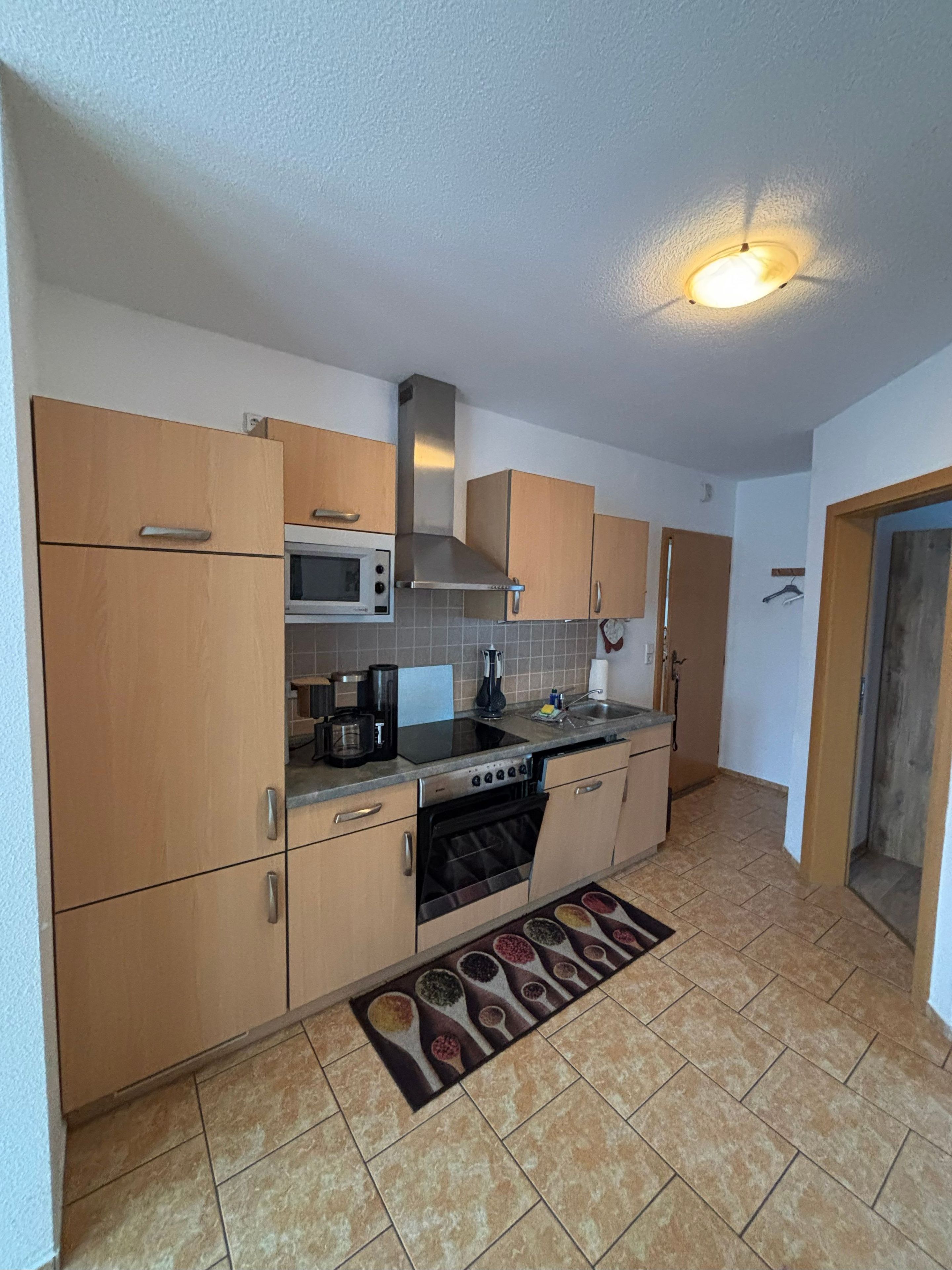 Une cuisine de taille réduite, dotée de meubles en bois, d’un four à micro-ondes, d’une cuisinière et d’un évier.
