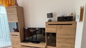 Un mueble de madera con televisor de pantalla plana, una mesita y un armario.