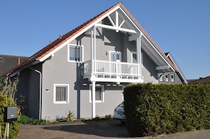 Ein zweistöckiges Haus mit Balkon, Garage und einer gepflegten Hecke.