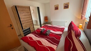 Un dormitorio con una cama, un armario, un radiador y dos cuadros en la pared.