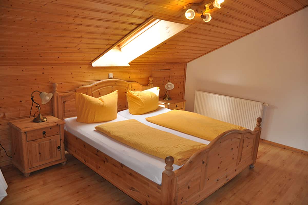Een houten kamer met een bed, nachtkastjes en een dakraam.