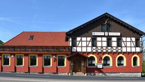 Ein traditionelles Gebäude mit roter Fassade und einem Fachwerkobergeschoss, mit Schildern für ein Gästehaus und ein Restaurant.