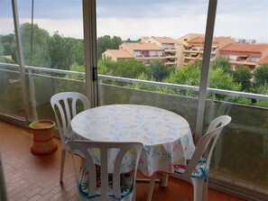 Un balcon avec une table et des chaises, donnant sur un quartier résidentiel.