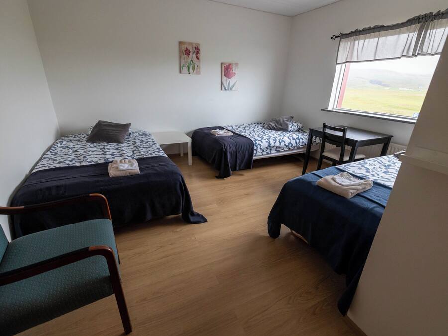 A room with two beds, a small table, and a chair.