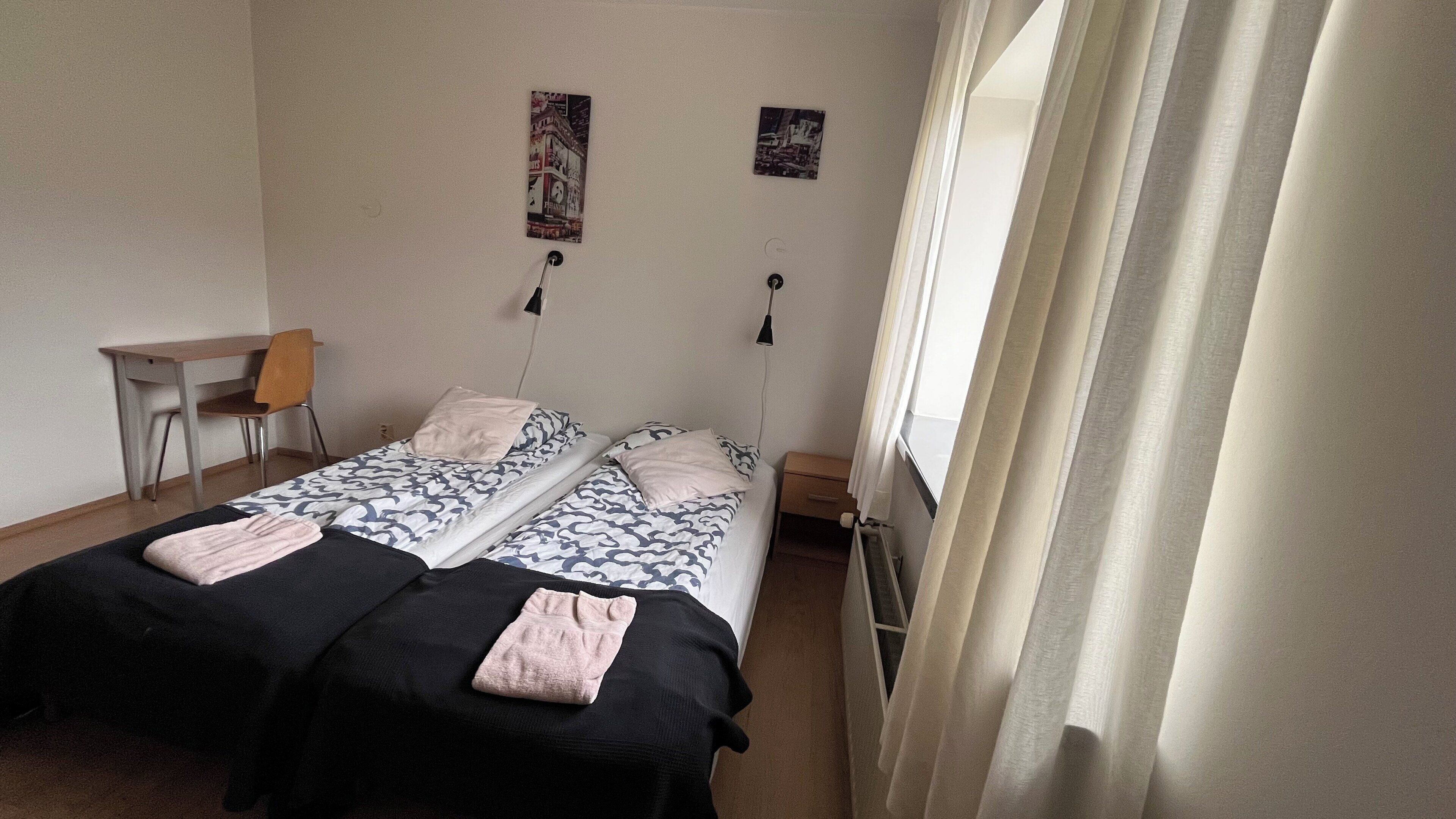 A bedroom with two beds, a desk, and a chair.