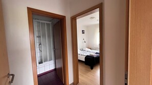 A hallway leading to a bedroom with a bed, a nightstand, and a window. - Grund guesthouse (Grundarfjörður)