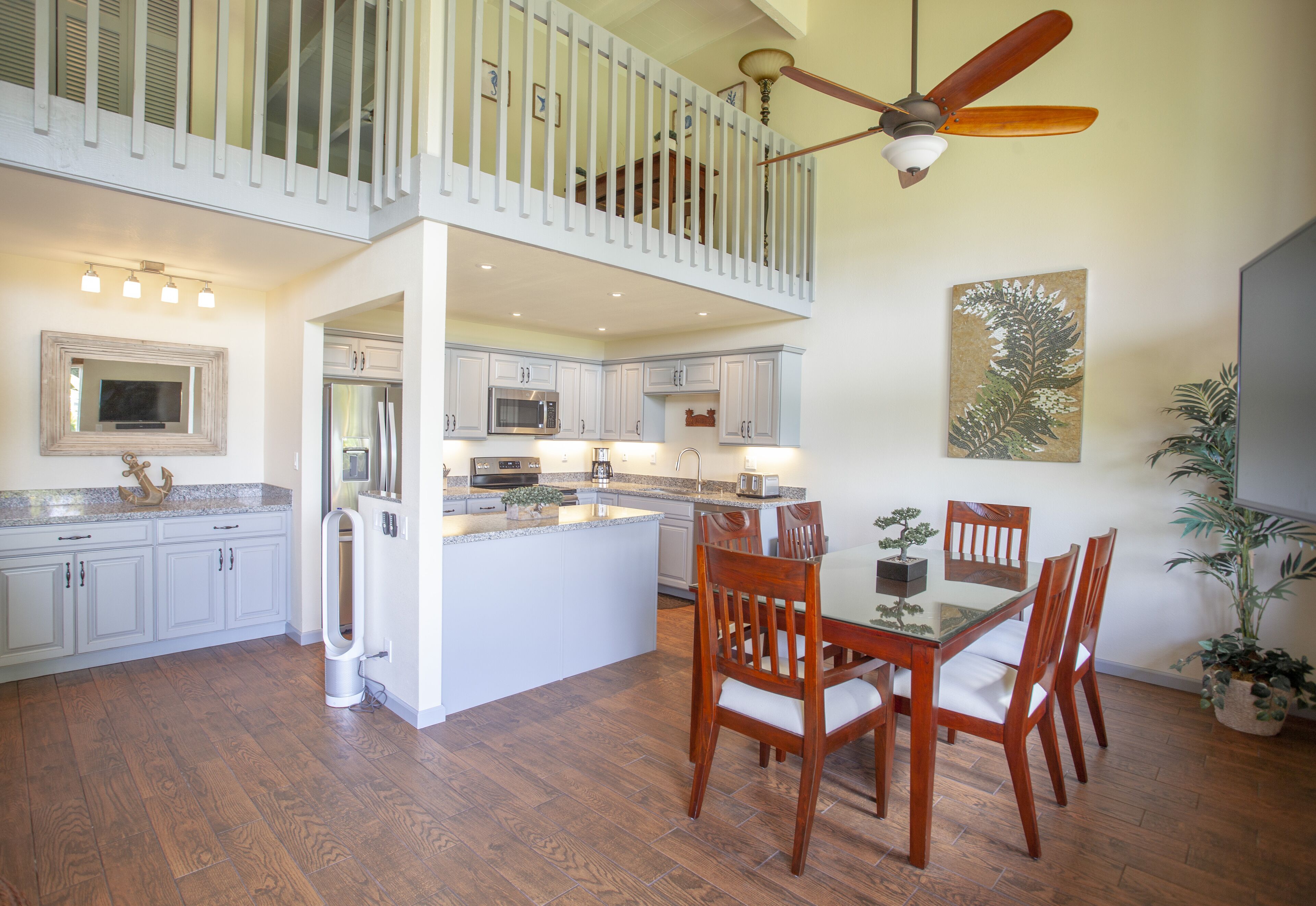 A spacious kitchen with a central island, white cabinetry, and a dining area with wooden chairs.