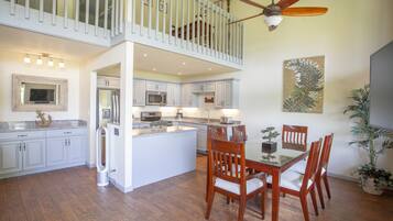 A spacious kitchen with a central island, white cabinetry, and a dining area with wooden chairs.