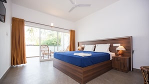 Un dormitorio con una cama grande, una mesita de noche, una lámpara, una silla y vistas al exterior a través de una puerta corredera.