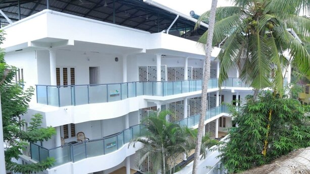 Un edificio de varios pisos con balcones, palmeras y un área exterior techada.