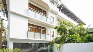 Un edificio moderno de varios pisos con techo plano, ventanas amplias y un área exterior cubierta con plantas en macetas.