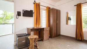 Una habitación con escritorio, armario y una pequeña mesa con sillas.
