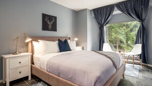 Une chambre moderne avec un grand lit, des tables de chevet, une chaise et une fenêtre avec des rideaux.