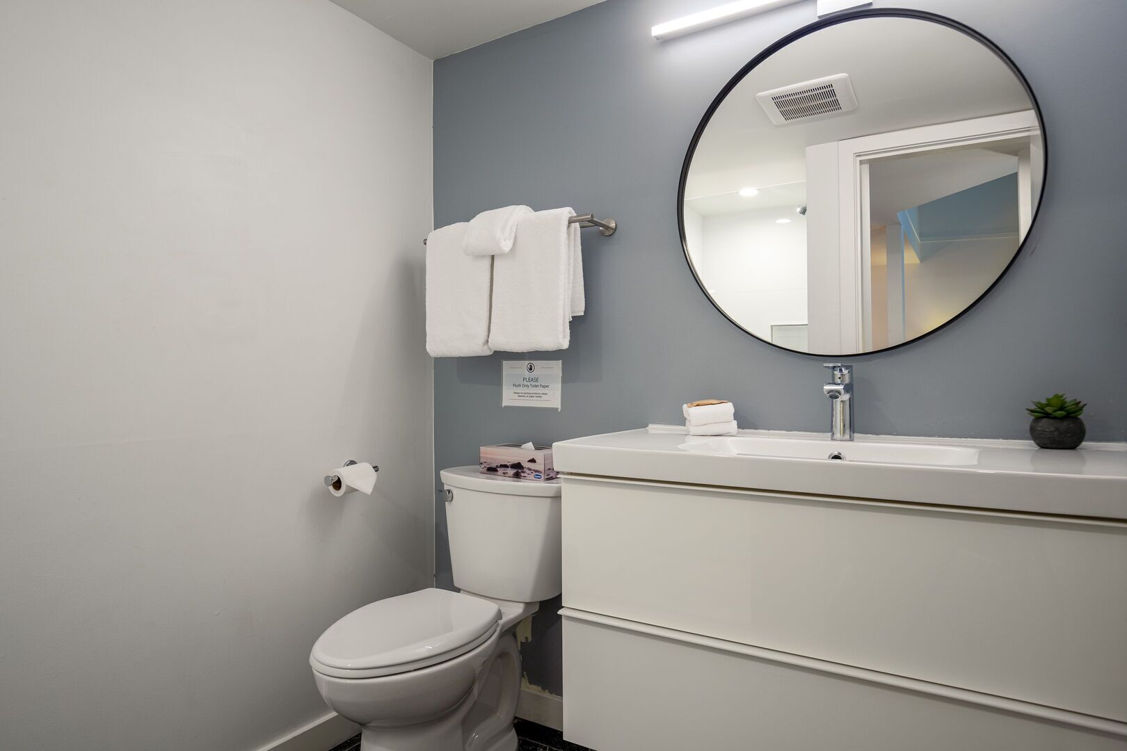 A bathroom with a toilet, sink, and mirror.