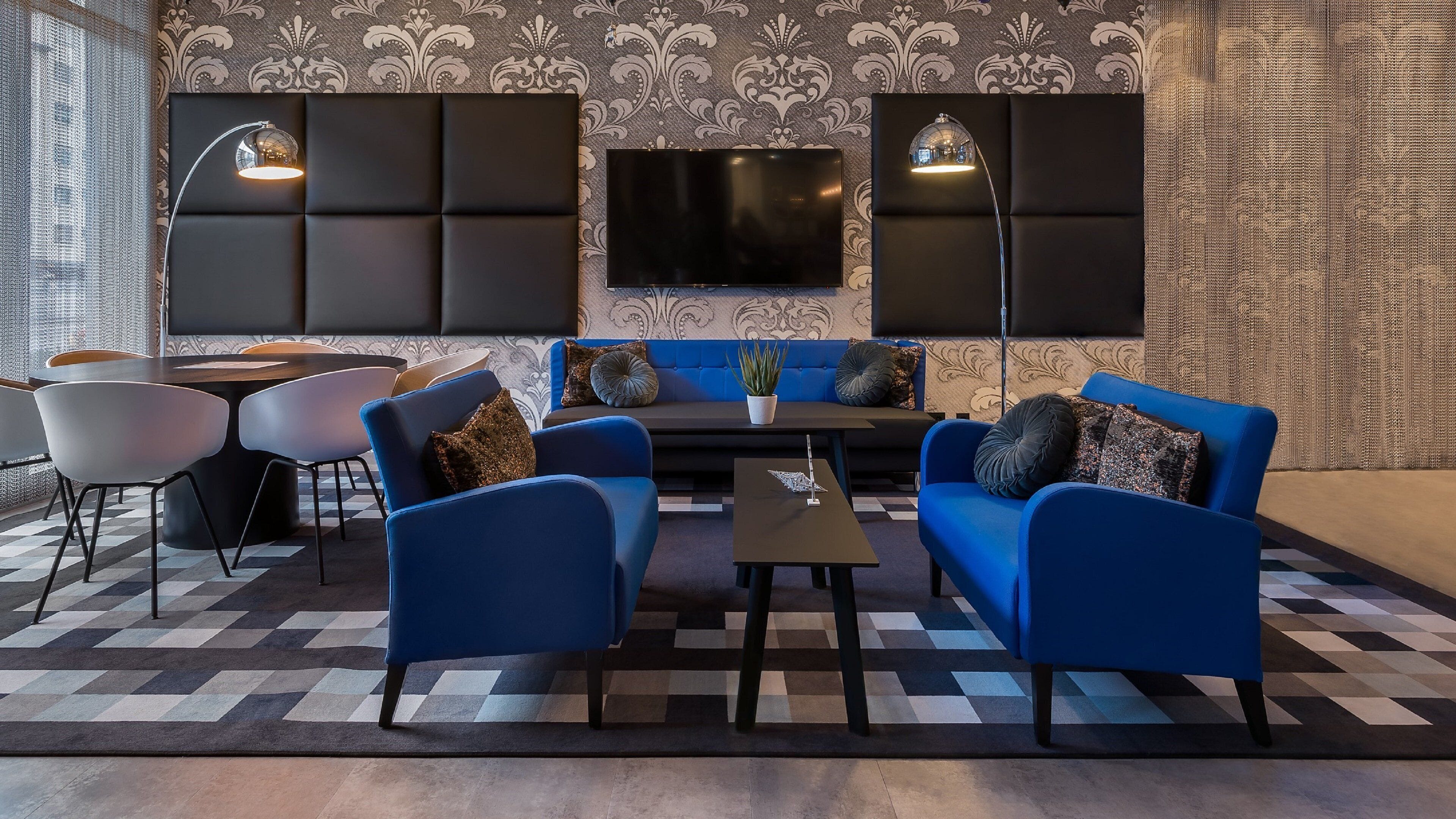 Una zona relax moderna con divani blu, un tavolino da caffè e una TV a schermo piatto montata a parete.