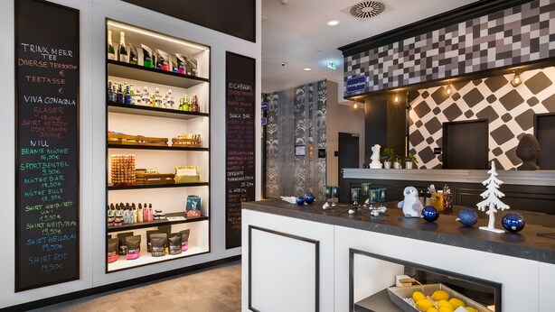 Un área de bar moderna con una variedad de bebidas y aperitivos exhibidos en estantes.